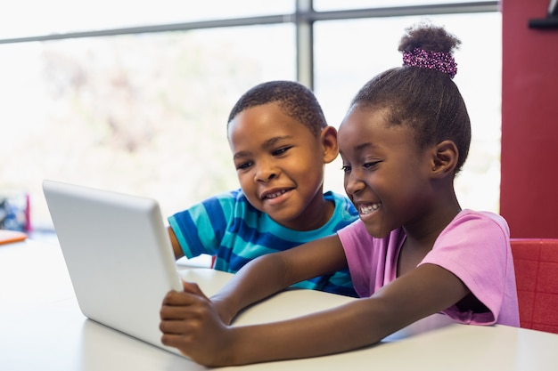 Niños de la escuela usando una tableta digital en el aula