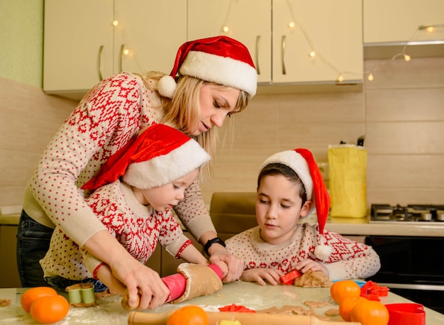 Los niños estadounidenses están preparando la masa, horneando galletas de jengibre en la cocina el día de invierno.