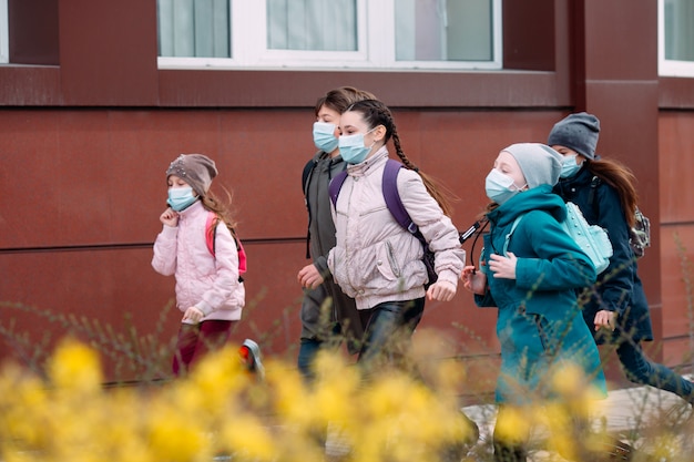 Los niños estudiantes con máscaras médicas abandonan la escuela.