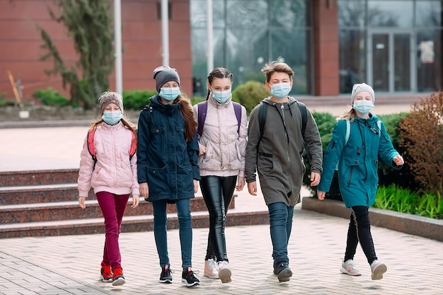 Los niños estudiantes con máscaras médicas salen de la escuela.