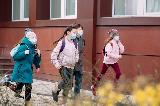 Los niños estudiantes con máscaras médicas salen de la escuela.
