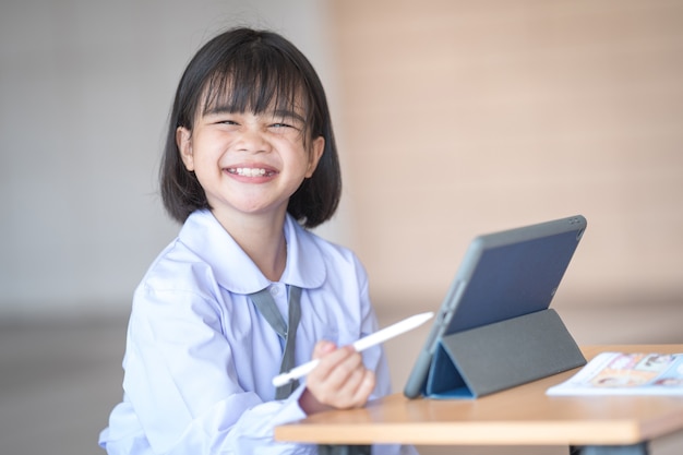 Los niños estudiantes de regreso a la escuela estudian juntos usando una tableta digital y escriben en un cuaderno en la escuela