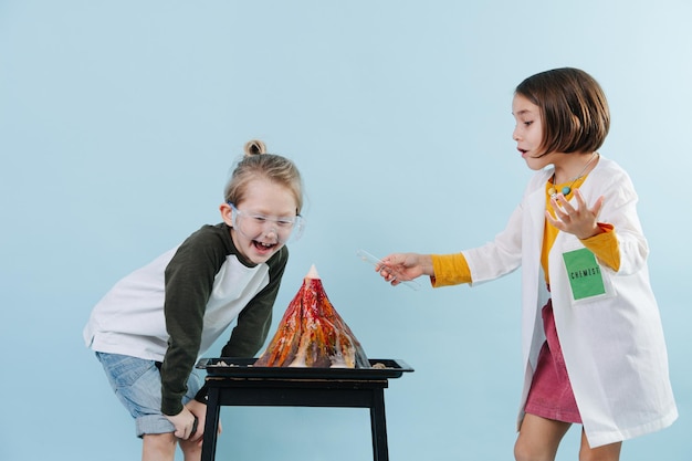 Niños exagerados haciendo un experimento de volcán químico divirtiéndose