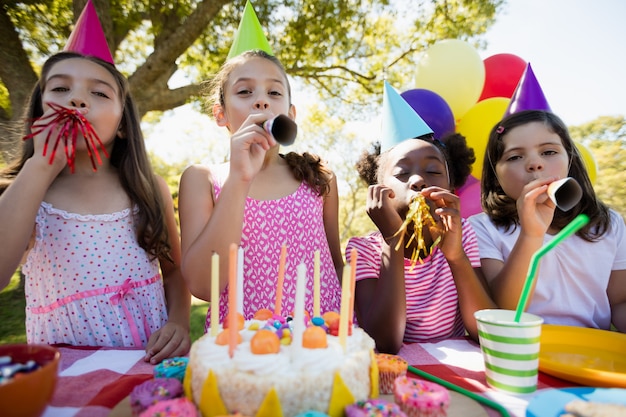 Niños exhalando en trompetas de cumpleaños durante una fiesta de cumpleaños