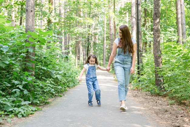 Los niños de la familia y el concepto de naturaleza retrato de mujer atractiva y niña pequeña caminando