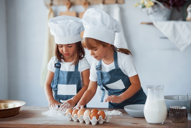 Niños de la familia en uniforme de chef blanco preparando la comida en la cocina.