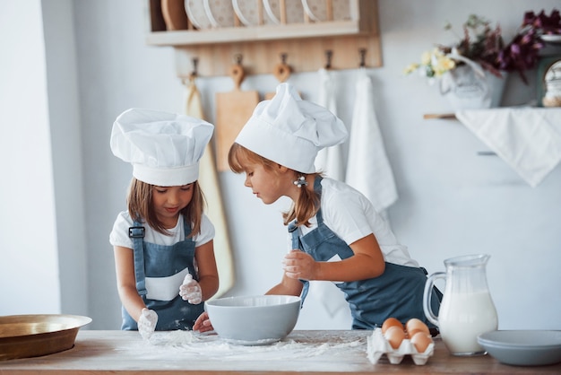 Niños de la familia en uniforme de chef blanco preparando la comida en la cocina.