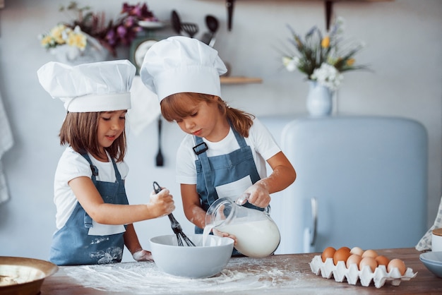 Niños de la familia en uniforme de chef blanco preparando la comida en la cocina.