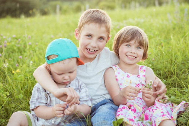 Niños felices abrazándose sentados en la hierba verde afuera