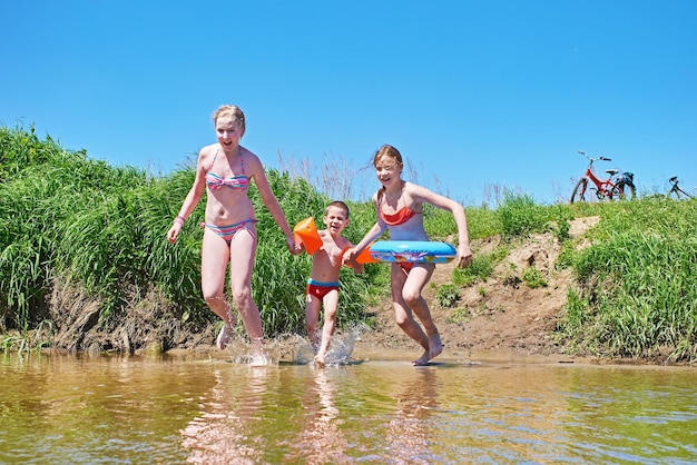 Los niños felices se bañan en el río el día de verano