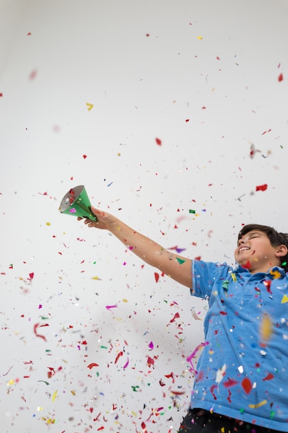 Niños felices celebrando la fiesta con soplar confeti