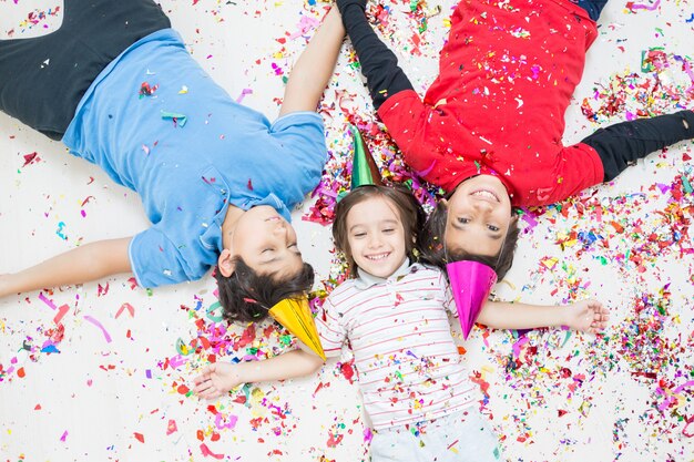 Niños felices celebrando la fiesta con soplar confeti