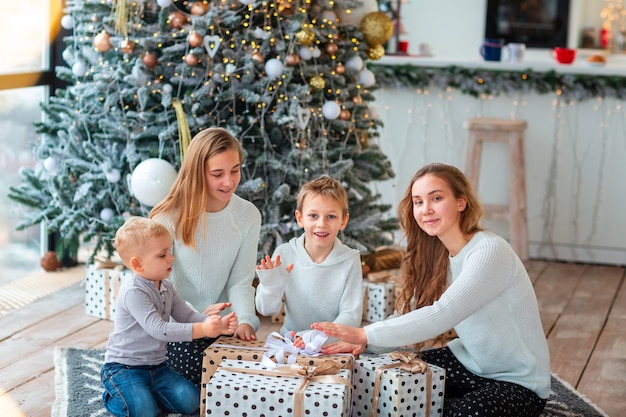 Niños felices cerca del árbol de Navidad con las cajas presentes.