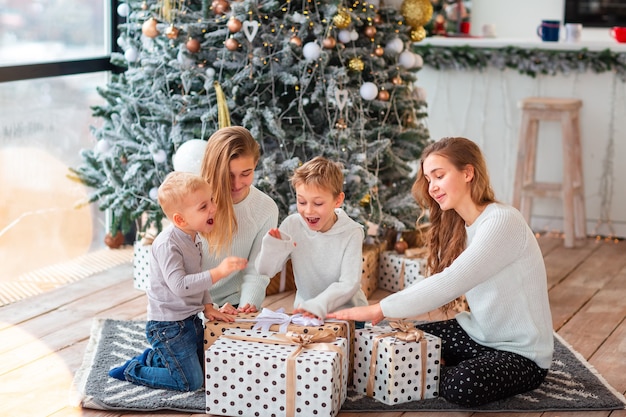 Niños felices cerca del árbol de Navidad con las cajas presentes.