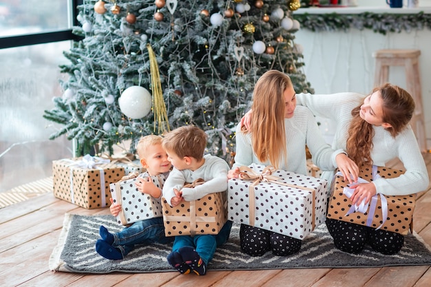 Niños felices cerca del árbol de Navidad con las cajas presentes.