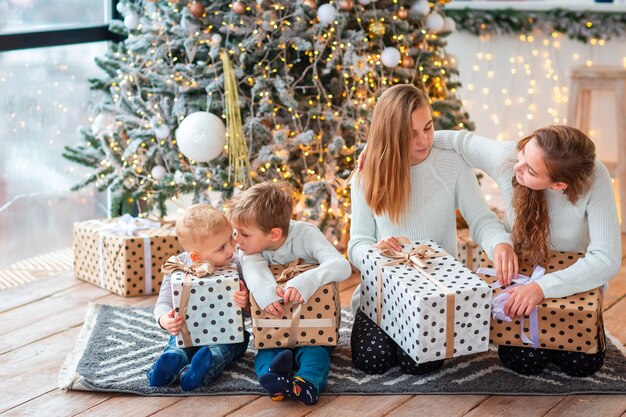 Niños felices cerca del árbol de Navidad con las cajas presentes.