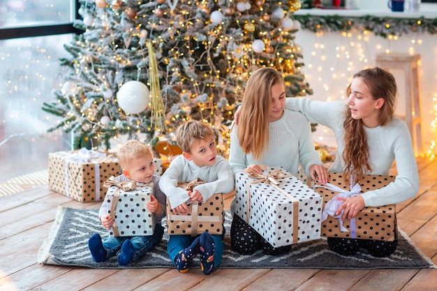 Niños felices cerca del árbol de Navidad con las cajas presentes.