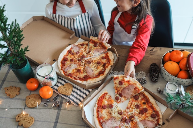 Niños felices comen pizza cena de Navidad El concepto de una clase magistral culinaria de Año Nuevo