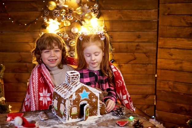 Niños felices crean casa de pan de jengibre de Navidad