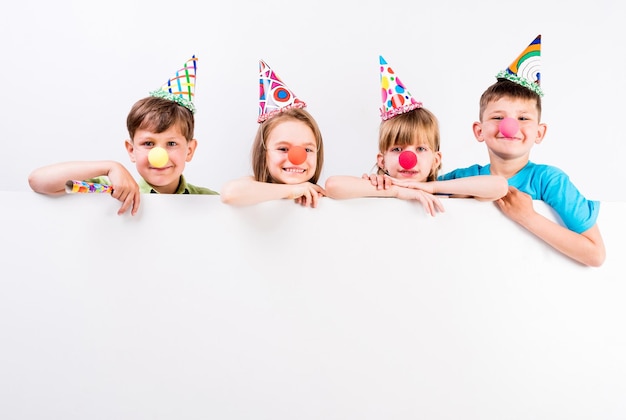niños felices con decoraciones navideñas y anuncios en blanco delante de ellos