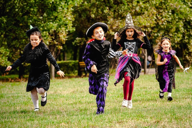 Niños felices en disfraces de halloween corriendo en el césped