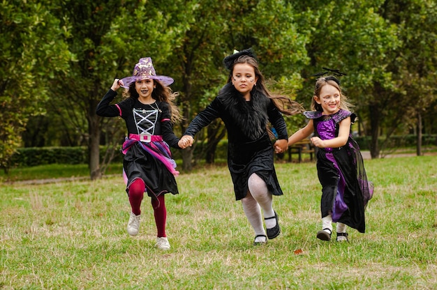 Niños felices en disfraces de halloween corriendo en el césped