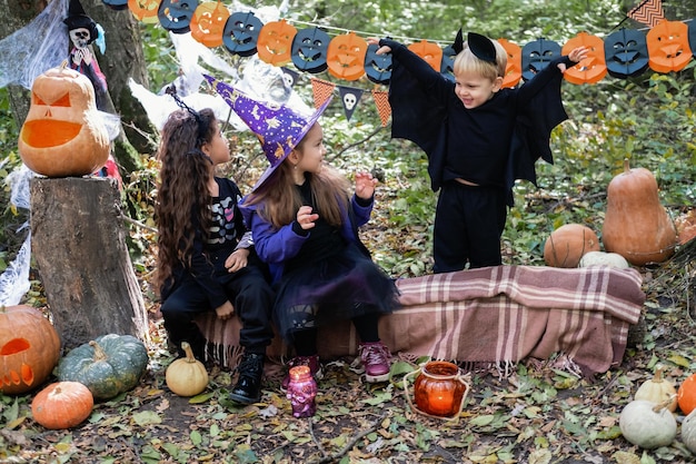 Foto niños felices en disfraces de halloween divirtiéndose en decoraciones de halloween al aire libre