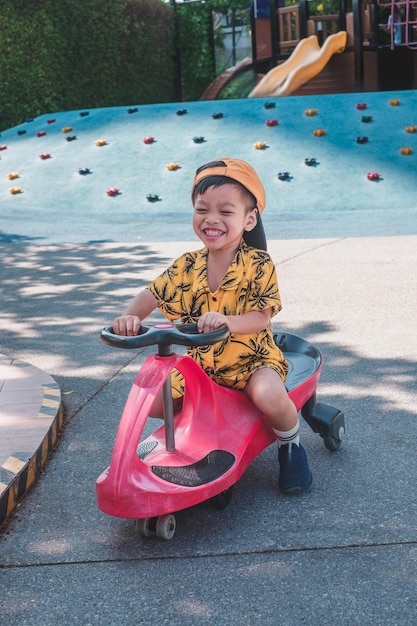 Niños felices disfrutando de juegos al aire libre en el parque con un tobogán de scooter y diversión en el patio de recreo