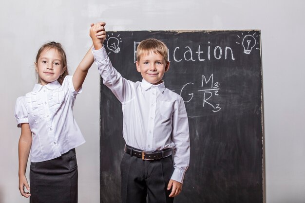 Niños felices de la escuela primaria en la pizarra de pared de clase