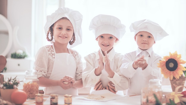 Niños felices en forma de chef para preparar deliciosos platos en la cocina