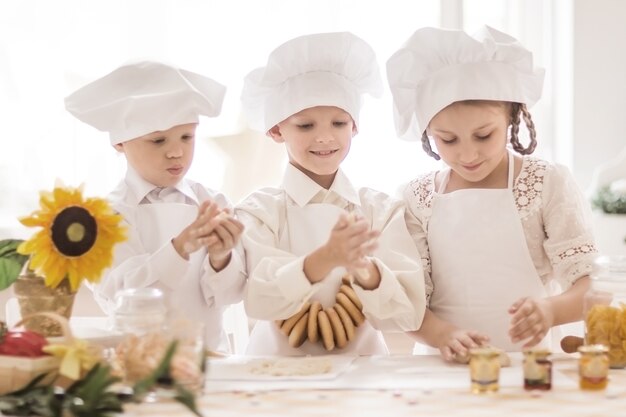 Niños felices en forma de chef para preparar deliciosos platos