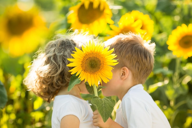 Niños felices con girasol jugando en el campo de primavera