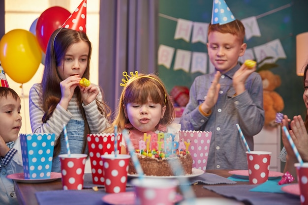 Niños felices con gorros de fiesta celebrando un cumpleaños