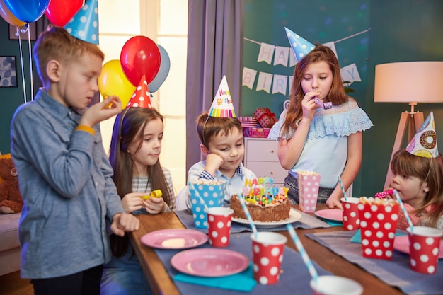 Niños felices con gorros de fiesta celebrando un cumpleaños