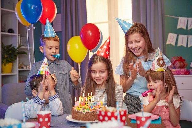 Niños felices con gorros de fiesta celebrando un cumpleaños