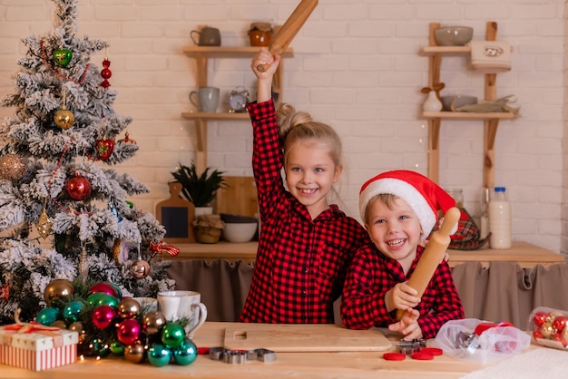 Los niños felices hornean galletas de Navidad en casa en la cocina