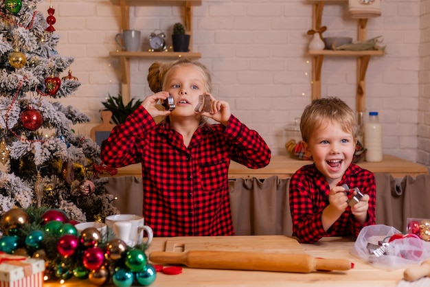 Los niños felices hornean galletas de Navidad en casa en la cocina