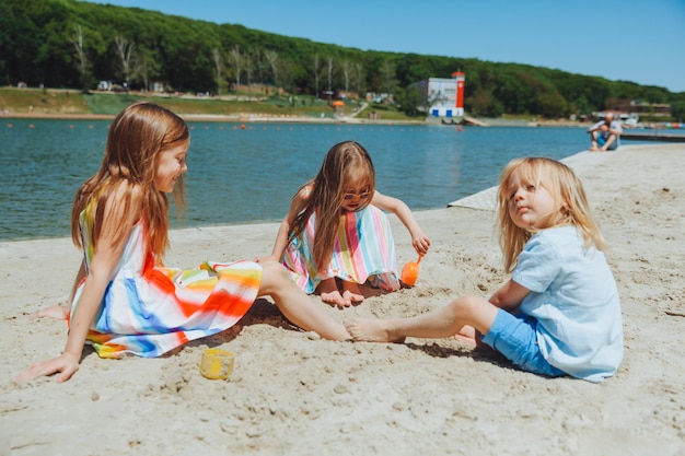 Niños felices juegan en la playa de arena de la ciudad en verano. Niño con síndrome de down.
