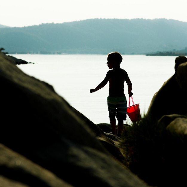 Niños felices jugando junto al mar en el fondo de la naturaleza