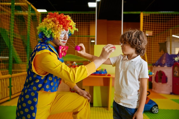 Niños felices jugando con un payaso masculino con un traje colorido y gracioso