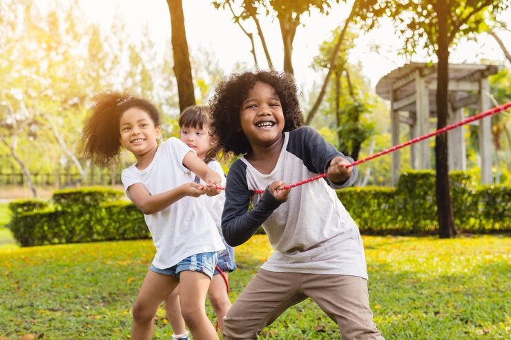 Foto niños felices jugando tirón de la cuerda en el parque