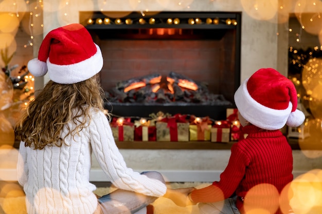 Niños felices junto a la chimenea en Navidad. Niños divirtiéndose en casa.