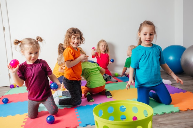 Niños felices lanzando pelotas en una canasta de plástico