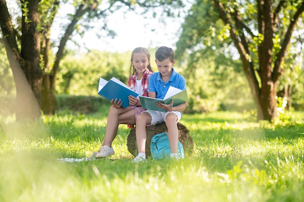 Niños felices leyendo en el parque en un día soleado