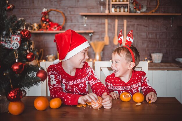 Niños felices con naranjas en la cocina oscura en casa en Nochebuena preparándose para las vacaciones feliz Navidad y feliz año nuevo