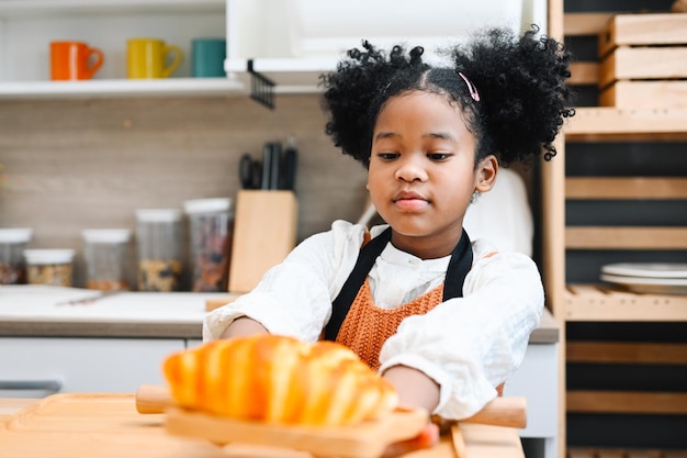 Niños felices niñas con pan y galletas jugando con harina y riendo en la cocina