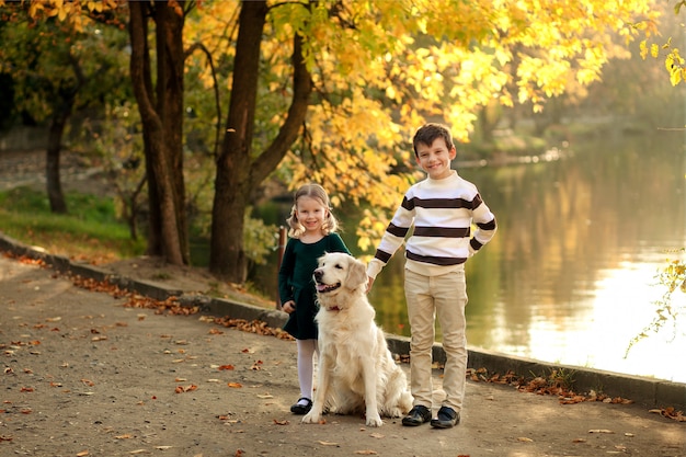 Niños felices con perro en el parque en otoño