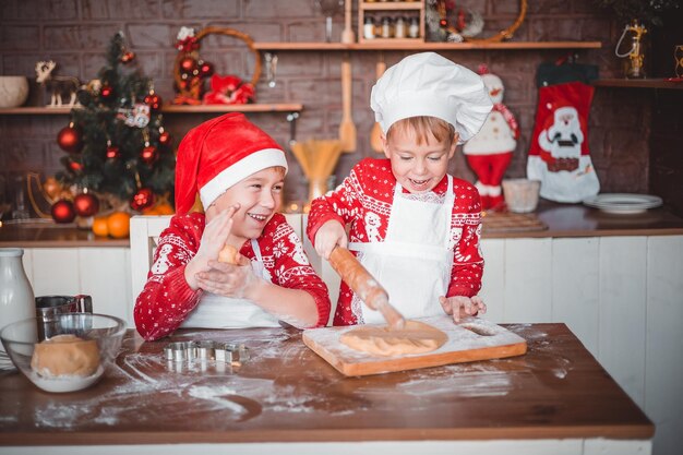 Niños felices preparan galletas festivas de Navidad en la cocina de la casa en Nochebuena feliz Navidad y feliz Año Nuevo vacaciones familiares