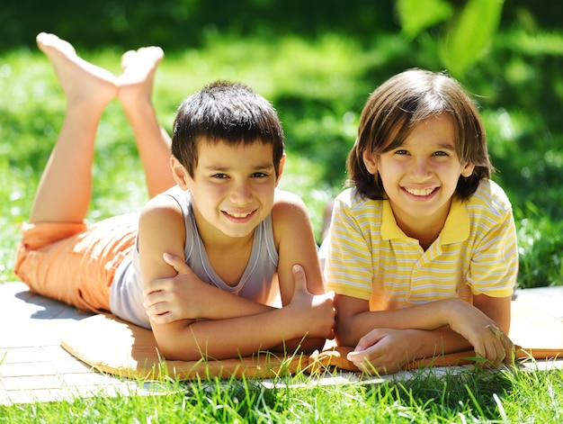 Niños felices que mienten en una hierba verde