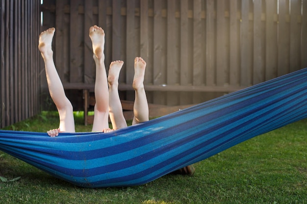 Niños felices relajándose en una hamaca al aire libre pies descalzos vacaciones vacaciones